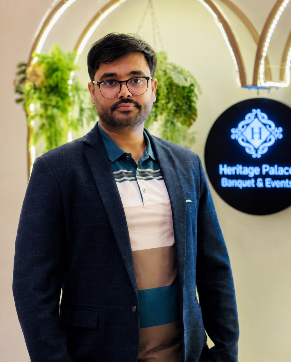 Portrait of a man wearing glasses and a navy blazer in an indoor venue